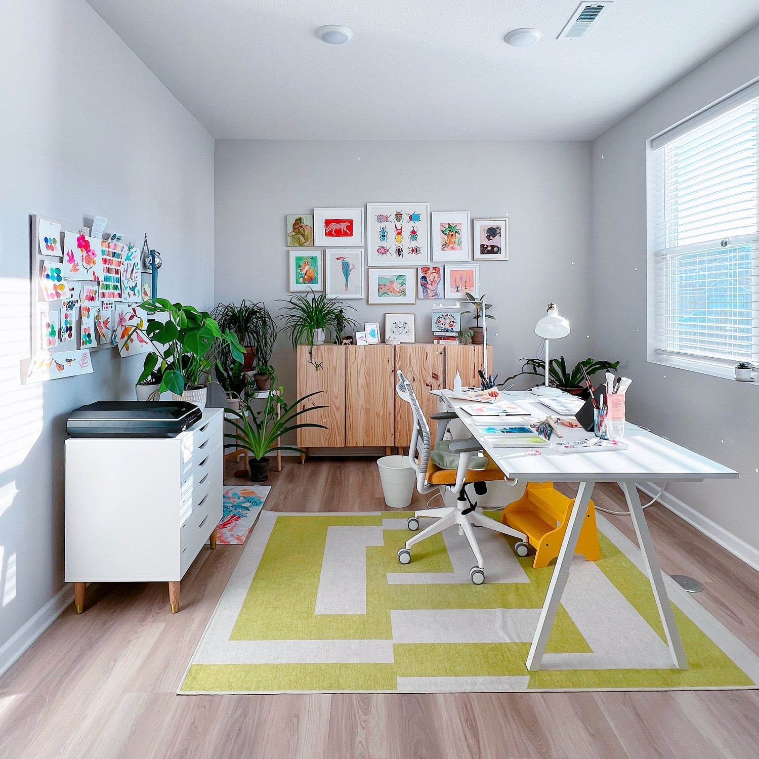 A cozy peek into Sun Lee’s art studio – a bright, creative space filled with colorful paints, brushes, and art supplies. Her desk is neatly arranged with works-in-progress, sketchbooks, and favorite tools, offering a glimpse into her artistic process and daily workspace.
