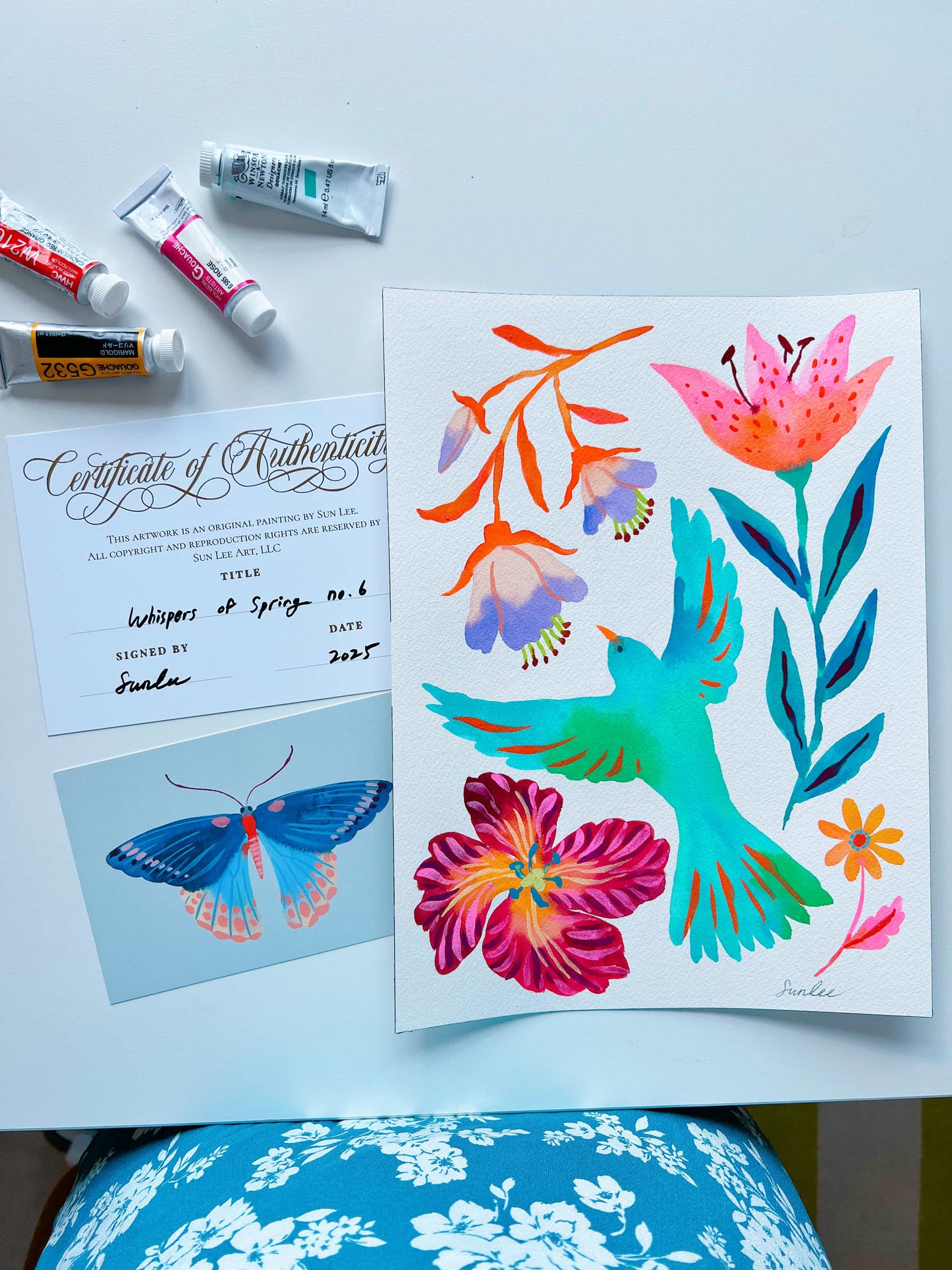 Original gouache, watercolor, and acrylic painting by Sun Lee from the 'Whispers of Spring' collection. This vibrant piece features a whimsical depiction of nature with bright flowers, butterflies, and birds, capturing the energy and beauty of spring. Perfect for nature lovers and those seeking aesthetic watercolor and gouache artwork, bringing joy and color to your space.