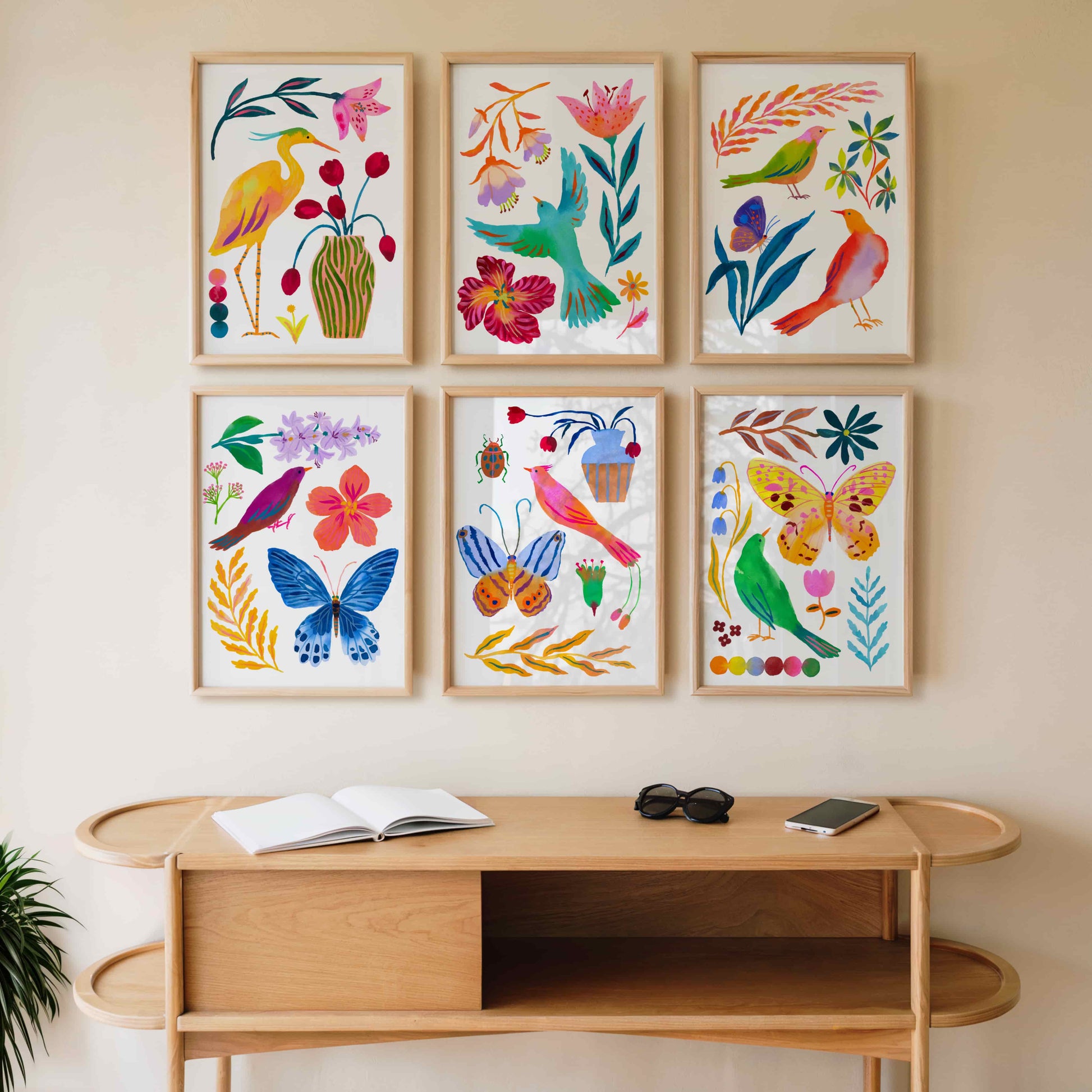 Set of six colorful framed artworks with floral and nature-themed designs on a white wall.