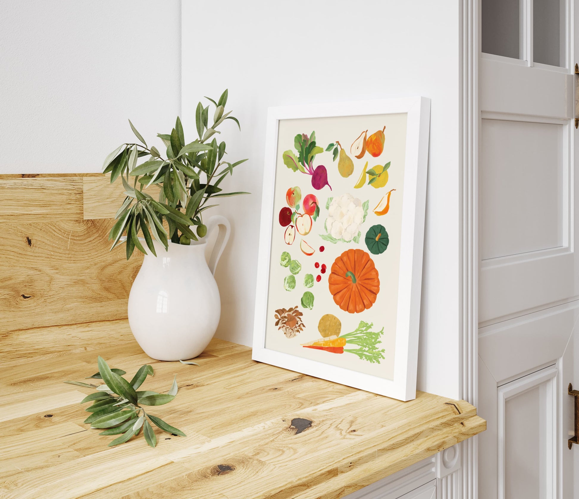 Framed artwork of fruits and vegetables on a wooden surface with a plant.