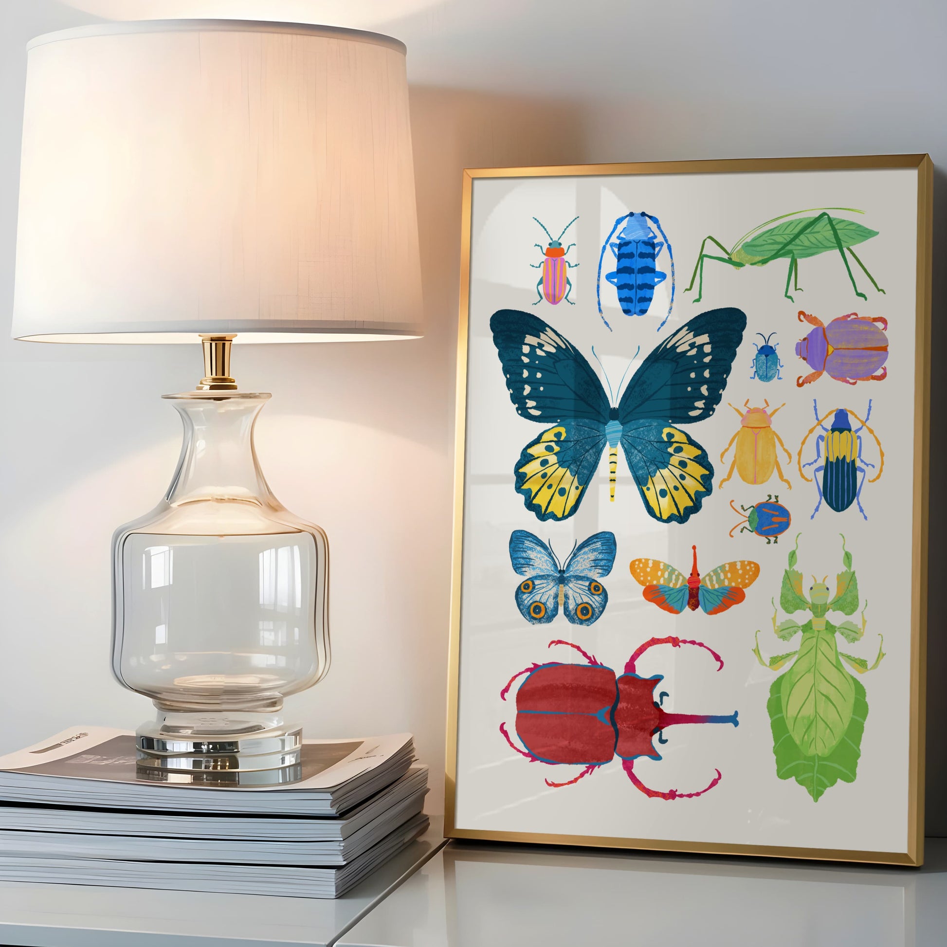 Framed artwork of colorful insects on a table next to a lamp