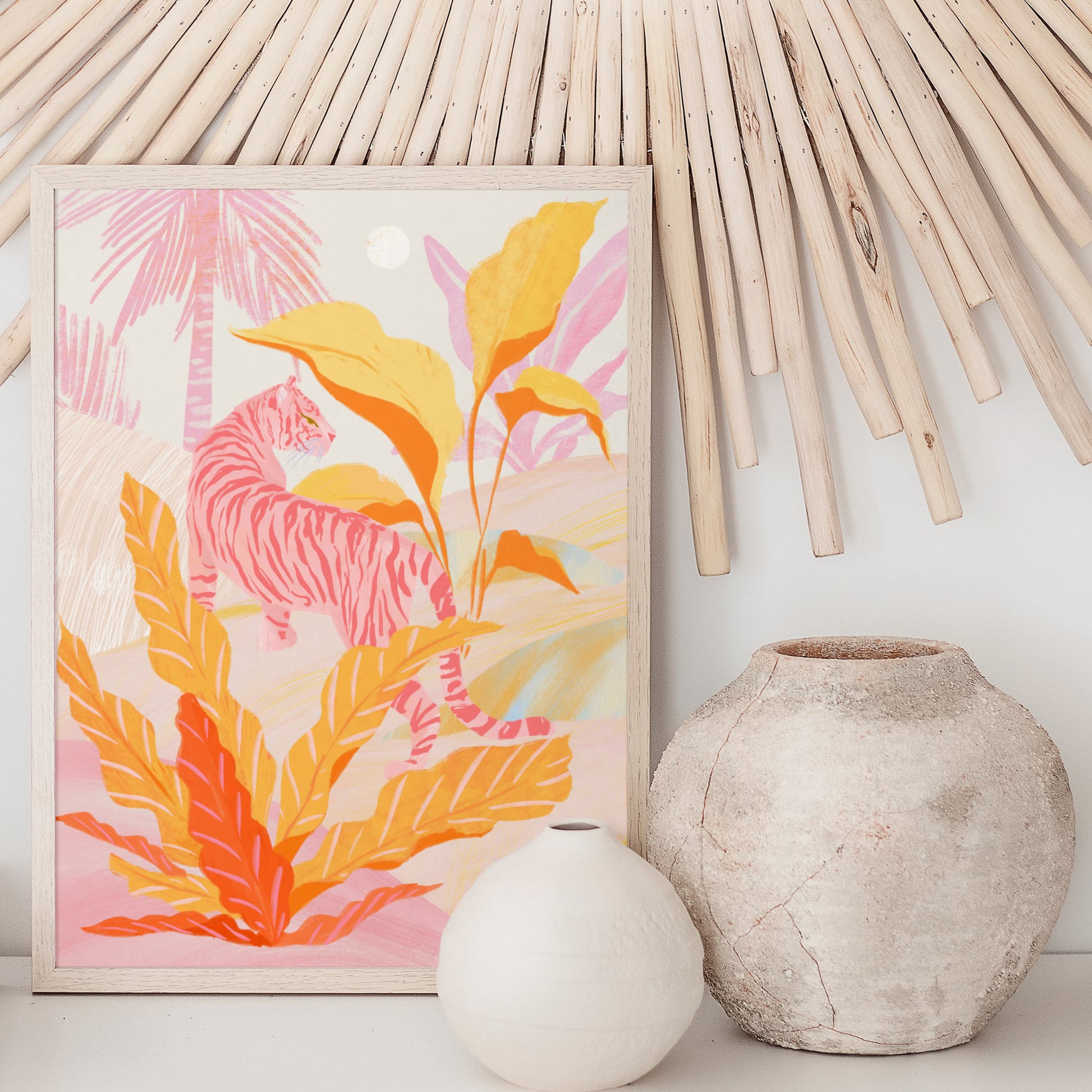 Framed artwork with colorful leaves and a tiger, placed on a surface with a white vase and a textured vase against a bamboo wall.
