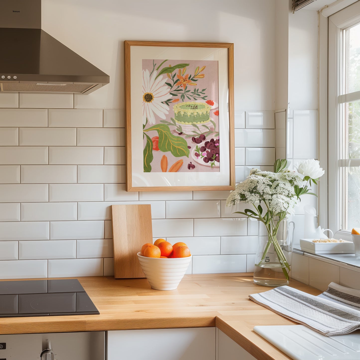 Kitchen with wooden countertop, bowl of oranges, vase of flowers, and framed artwork on the wall.