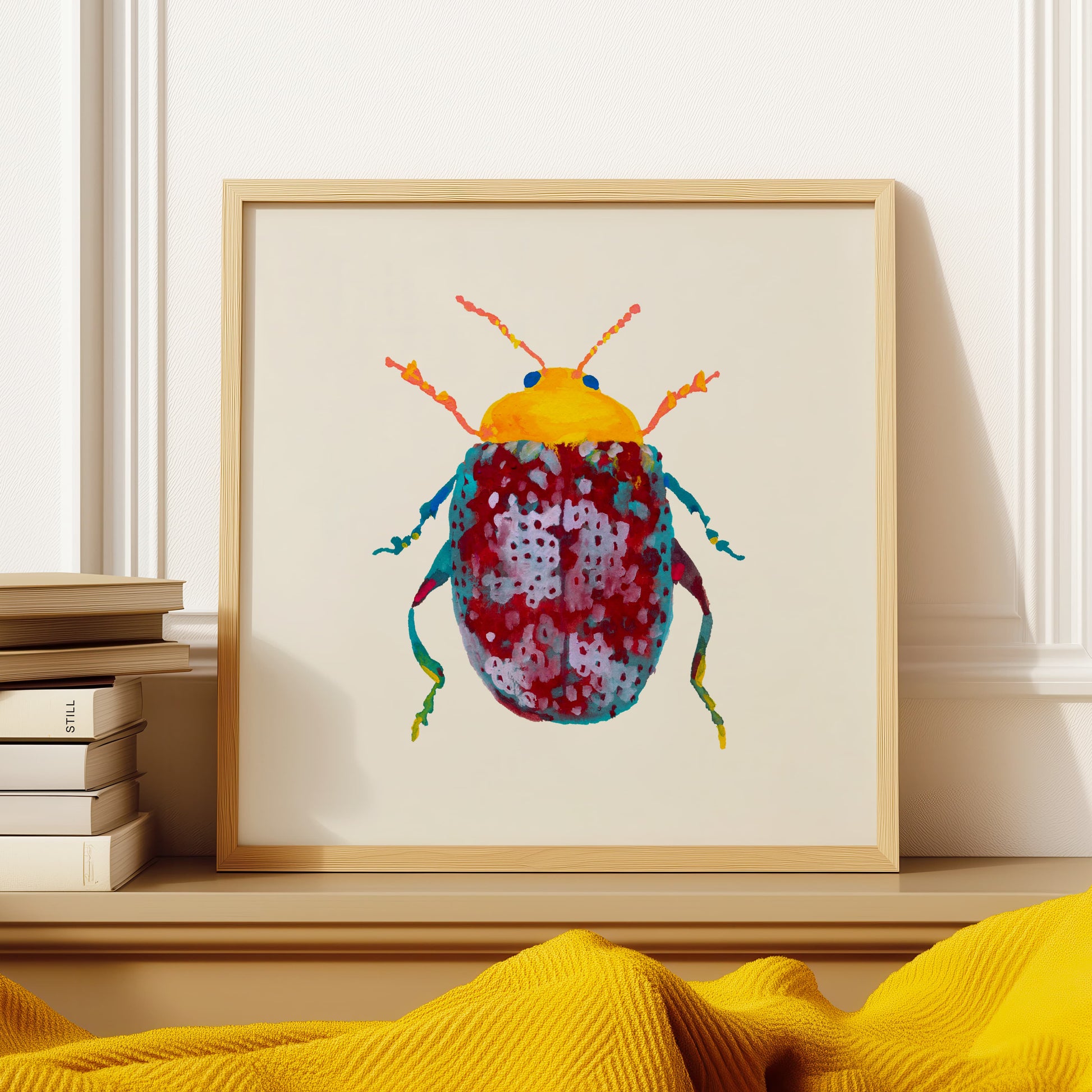 Framed artwork of a colorful beetle on a shelf with books and yellow fabric.