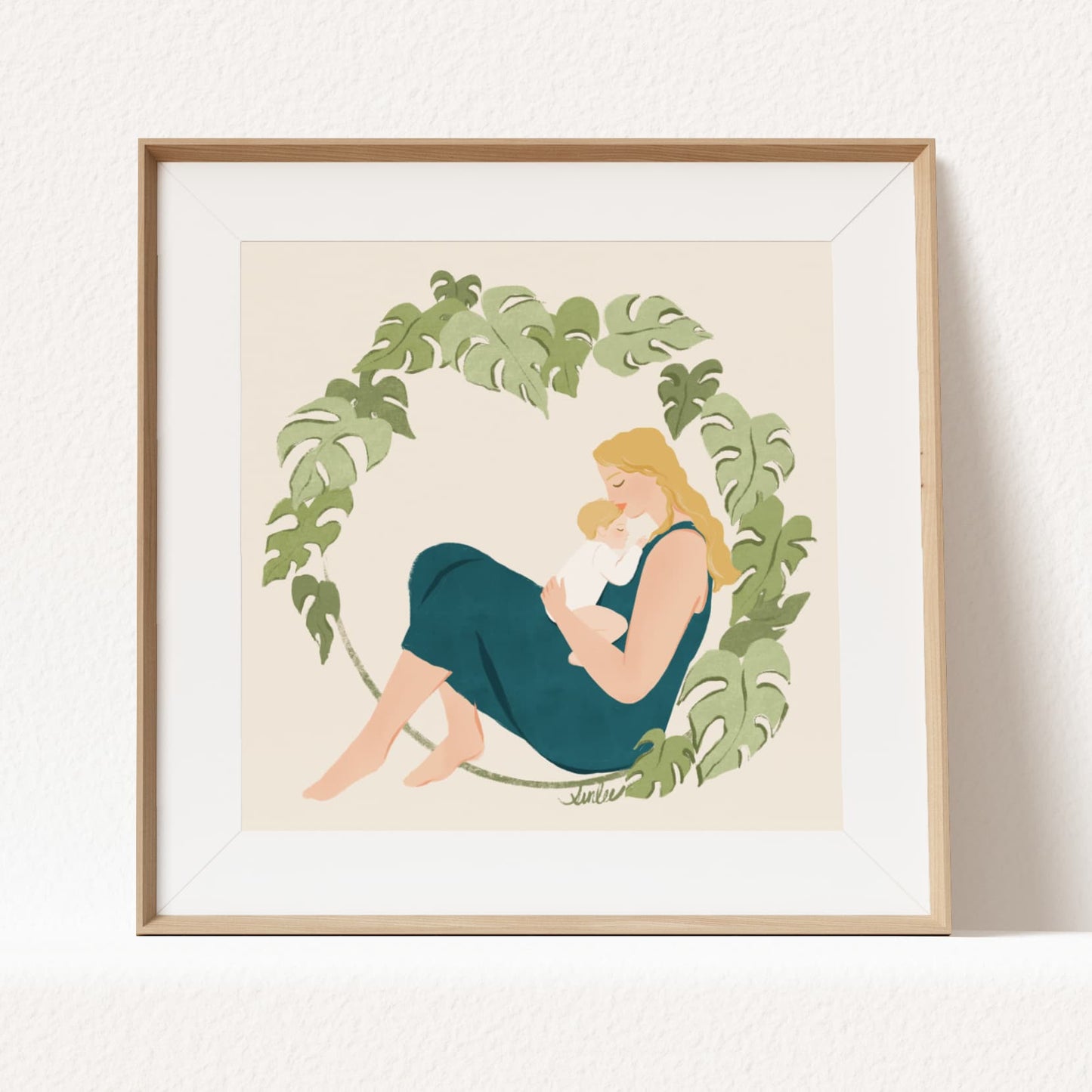 Framed artwork of a mother and child surrounded by green leaves on a beige background by Sun Lee